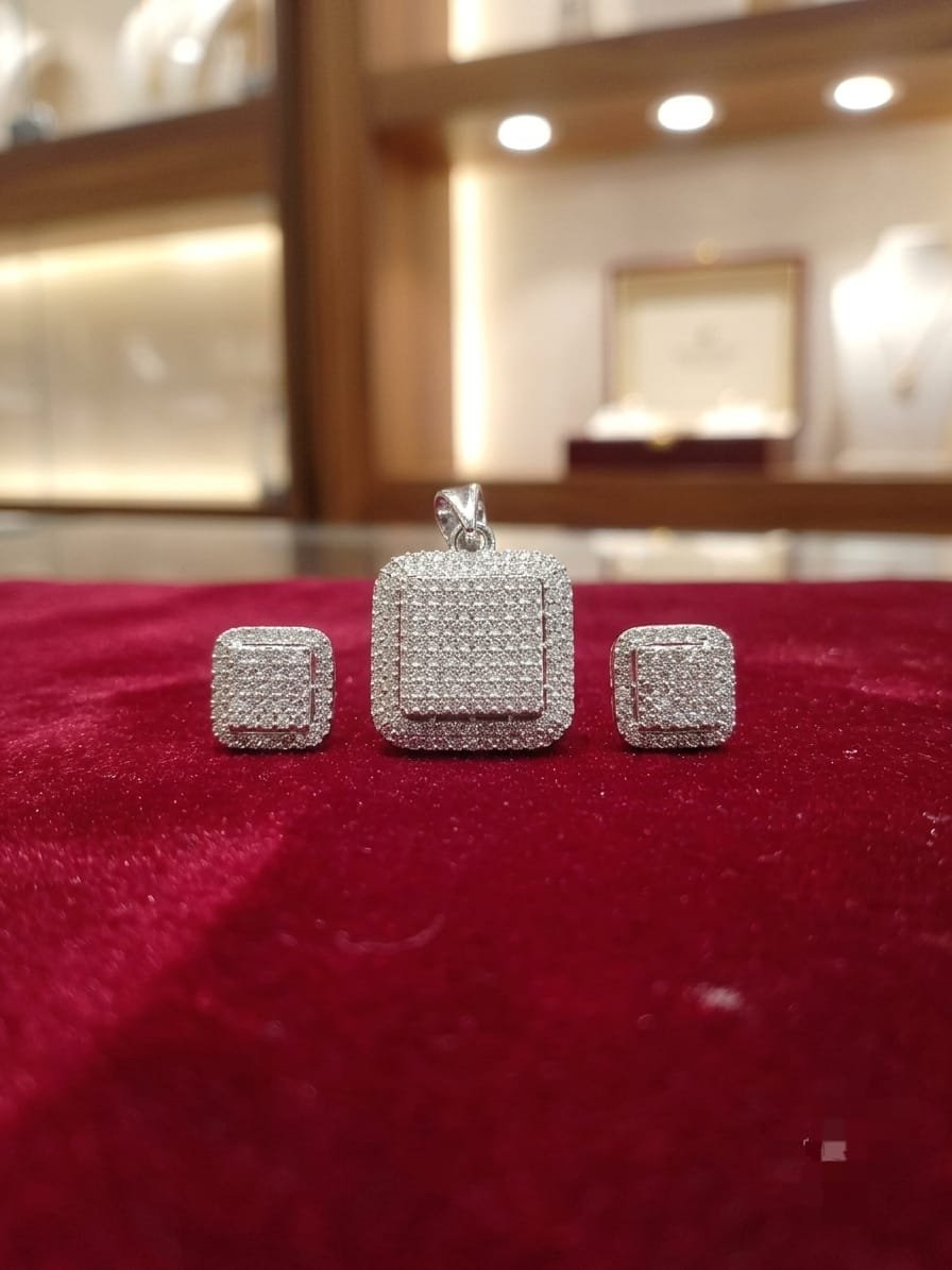 Square-shaped, pave-set diamond or cubic zirconia pendant and matching earrings in a silver-toned metal setting.