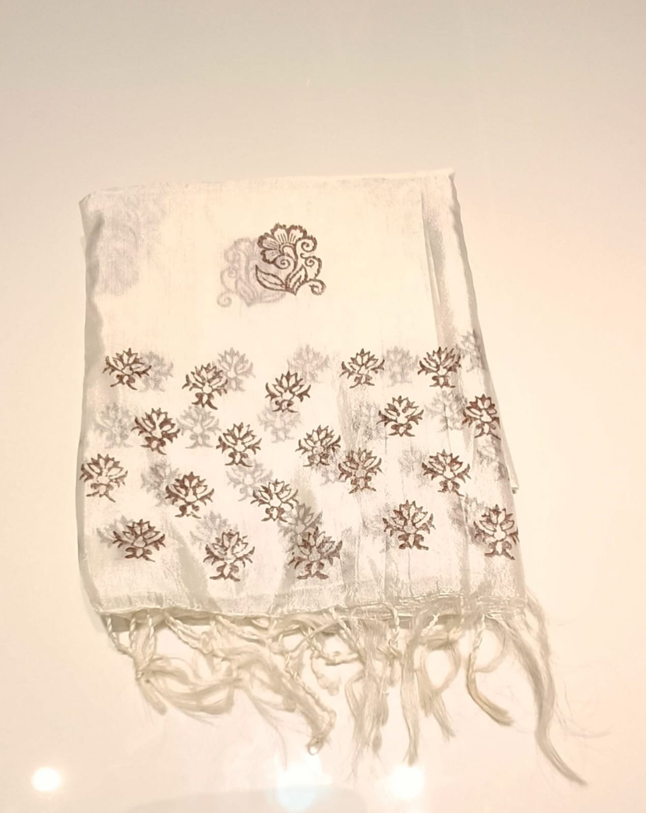 Pretty white printed fabric or stole featuring brown and grey floral motifs with fringed tassel edges.